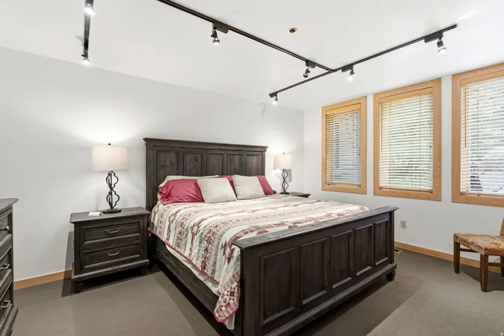 Spacious room featuring three large windows with wood-finish trim, recessed track lighting, and soft carpet flooring