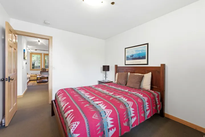 Bedroom featuring neutral wall paint, dark carpet flooring, and a solid wood door frame leading to another room