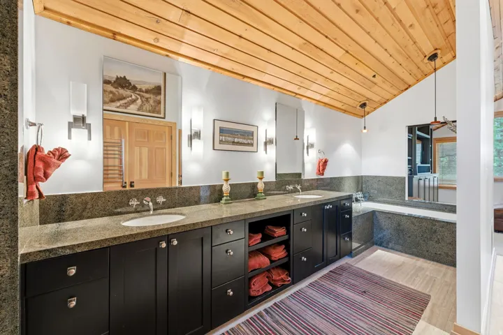 Spacious bathroom featuring a dual vanity with a stone countertop, individual vessel sinks, and ample storage cabinetry