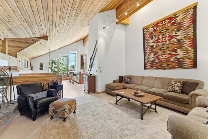 Vaulted wood-paneled ceilings with exposed beams, open-concept design, and light-tone flooring