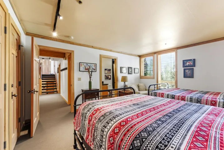 Bedroom featuring wood trim, two windows with blinds, track lighting, and a neutral wall color