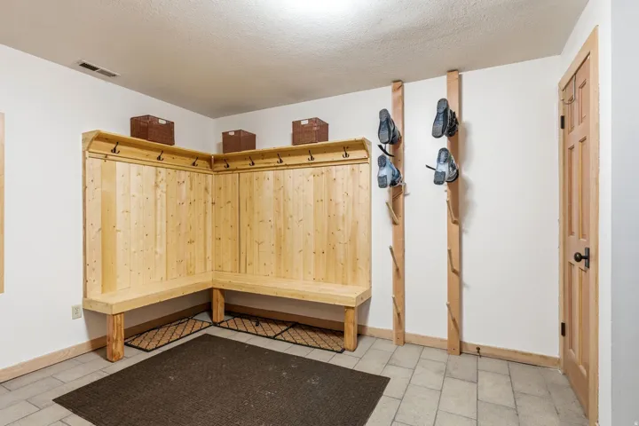 Built-in wood mudroom bench with coat hooks and overhead storage