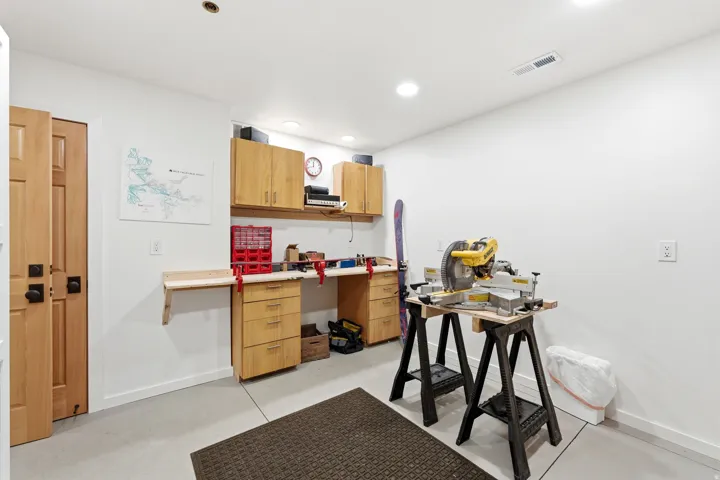 Dedicated workspace featuring light wood cabinetry, a built-in workbench, and recessed lighting