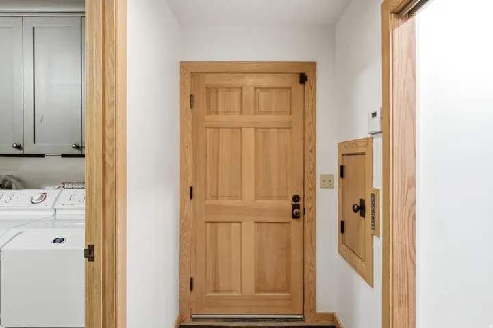 Six-panel wood door with black hardware, wood-frame doorway, and wood-finish trim
