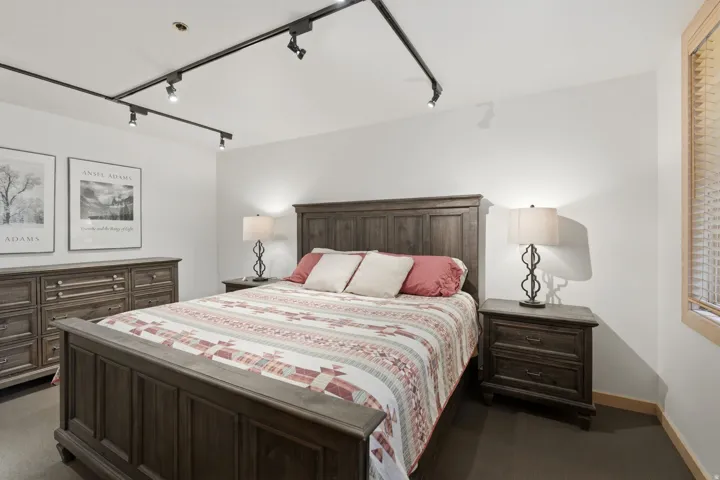 Bedroom featuring dark wood-finish flooring, white walls, and track lighting