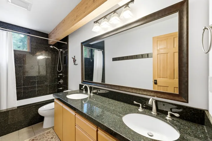 Bathroom featuring a dual vanity with a dark speckled countertop and undermount sinks