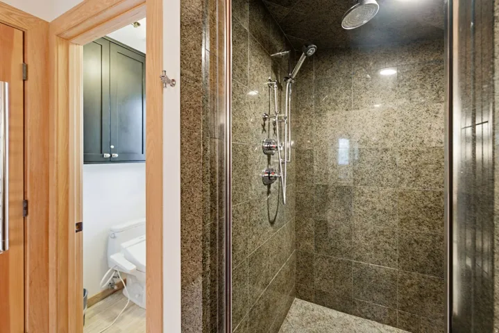 Enclosed shower featuring full-height stone-finish tile walls and a coordinating stone-finish tile floor