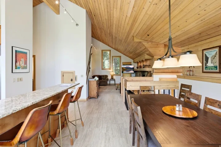 Spacious interior featuring a wood-paneled vaulted ceiling, recessed lighting, and a large dining table with seating