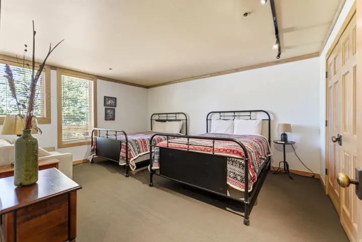 Spacious room with dual windows featuring wooden blinds and trim, a panel door with brass hardware, and track lighting