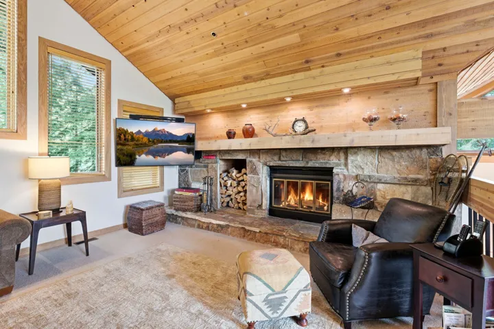 Stone-clad fireplace with a wood mantel and built-in wood storage