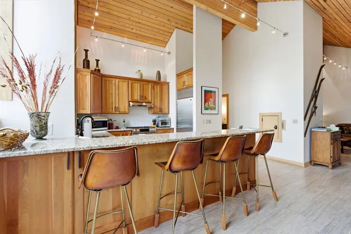 Kitchen island with a light-toned countertop, wood-finish cabinetry, and stainless steel appliances