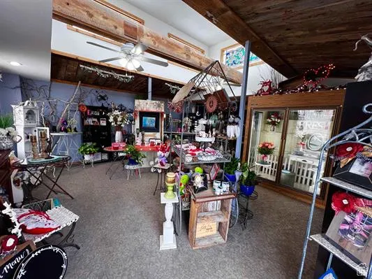 Miscellaneous room with beam ceiling, ceiling fan, and carpet flooring