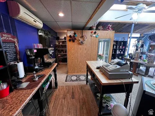 Interior space with a drop ceiling, dark hardwood / wood-style floors, an AC wall unit, and ceiling fan