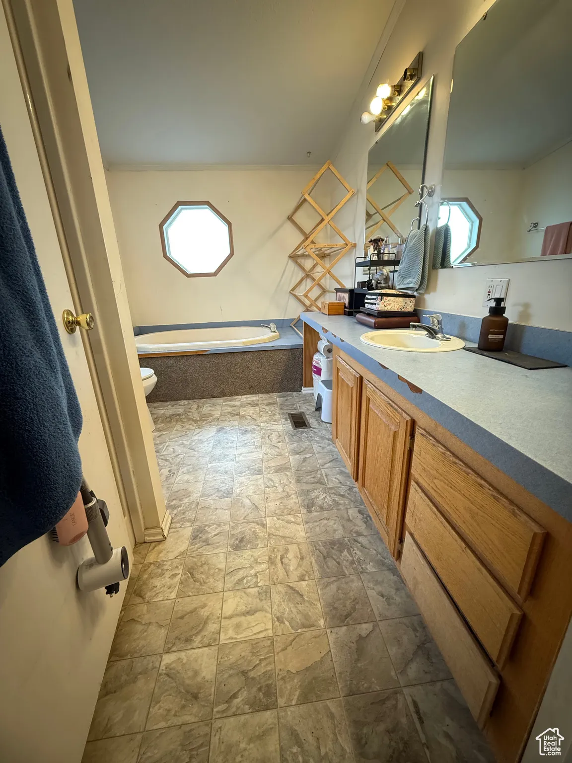 Bathroom with tiled tub, vanity, and toilet
