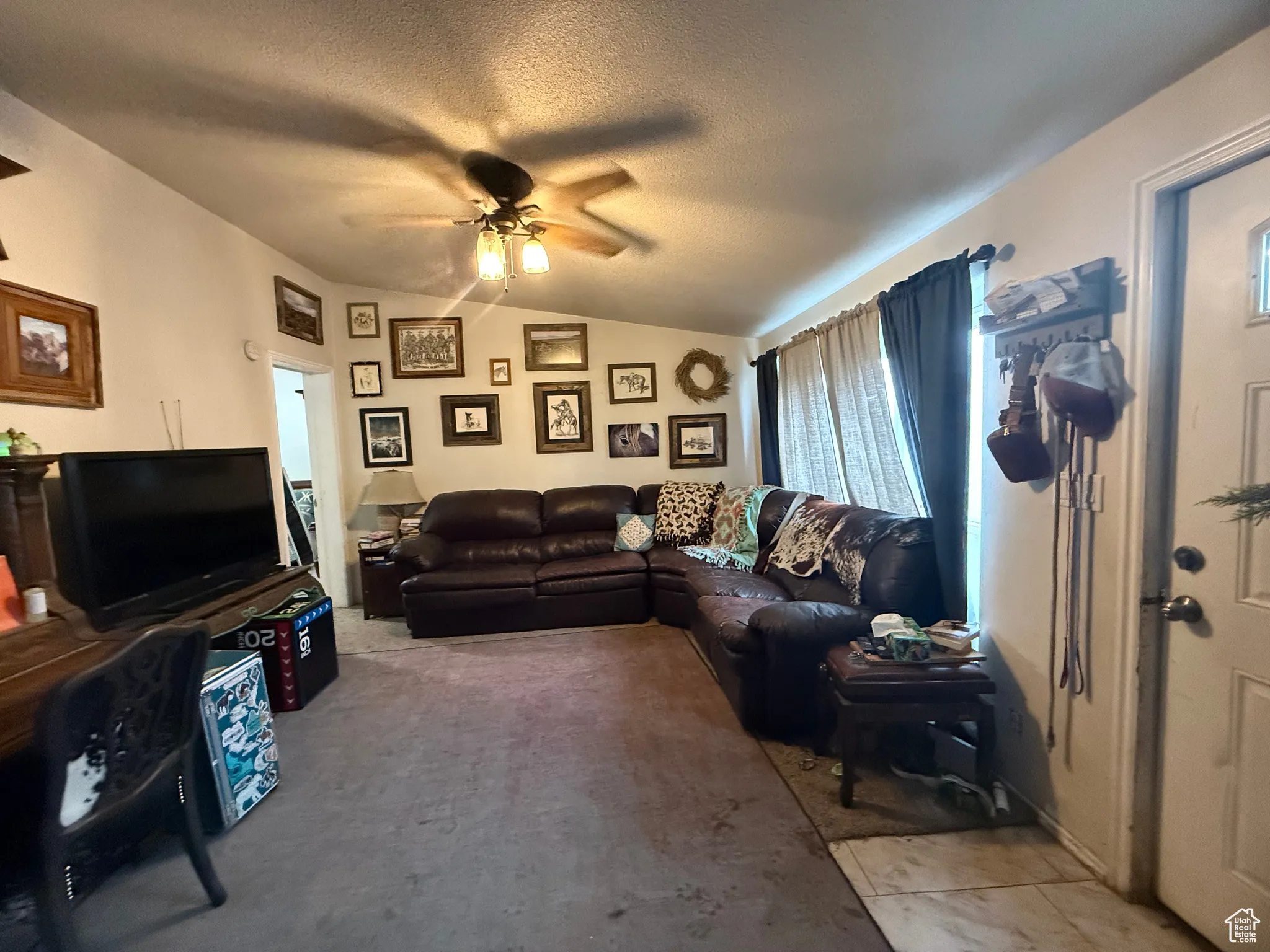Living room with ceiling fan, lofted ceiling, and a textured ceiling