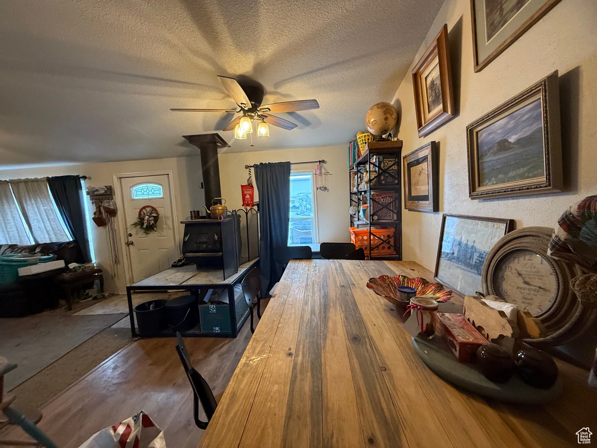 Dining area featuring hardwood / wood-style flooring, ceiling fan, a wood stove, and a textured ceiling