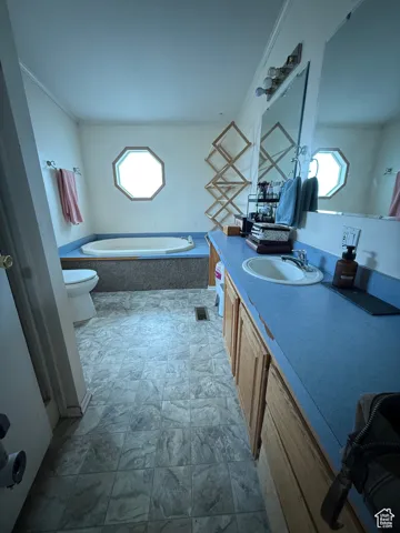 Bathroom with a relaxing tiled tub, vanity, a wealth of natural light, and toilet
