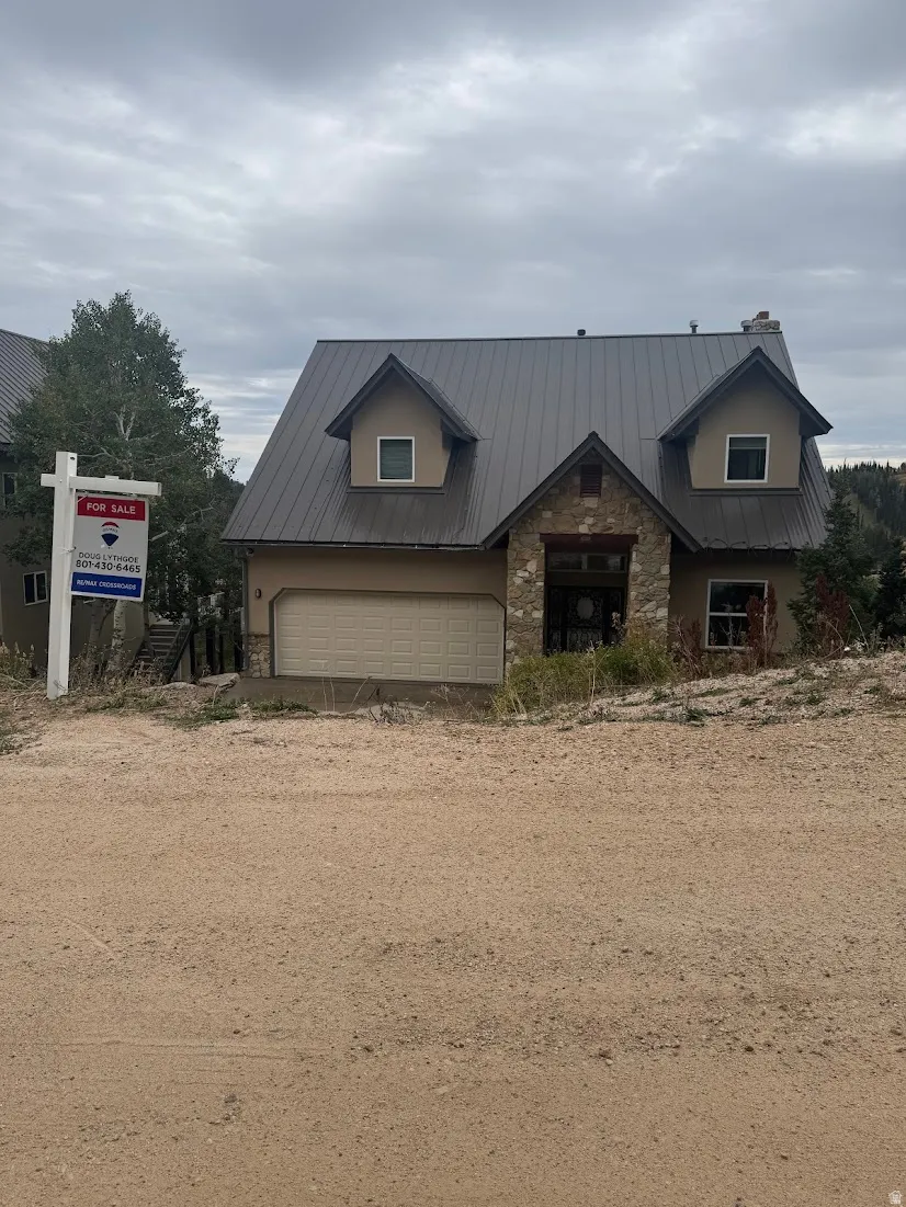 Two-story residence featuring a metal roof, dormer windows, and a stone facade accent