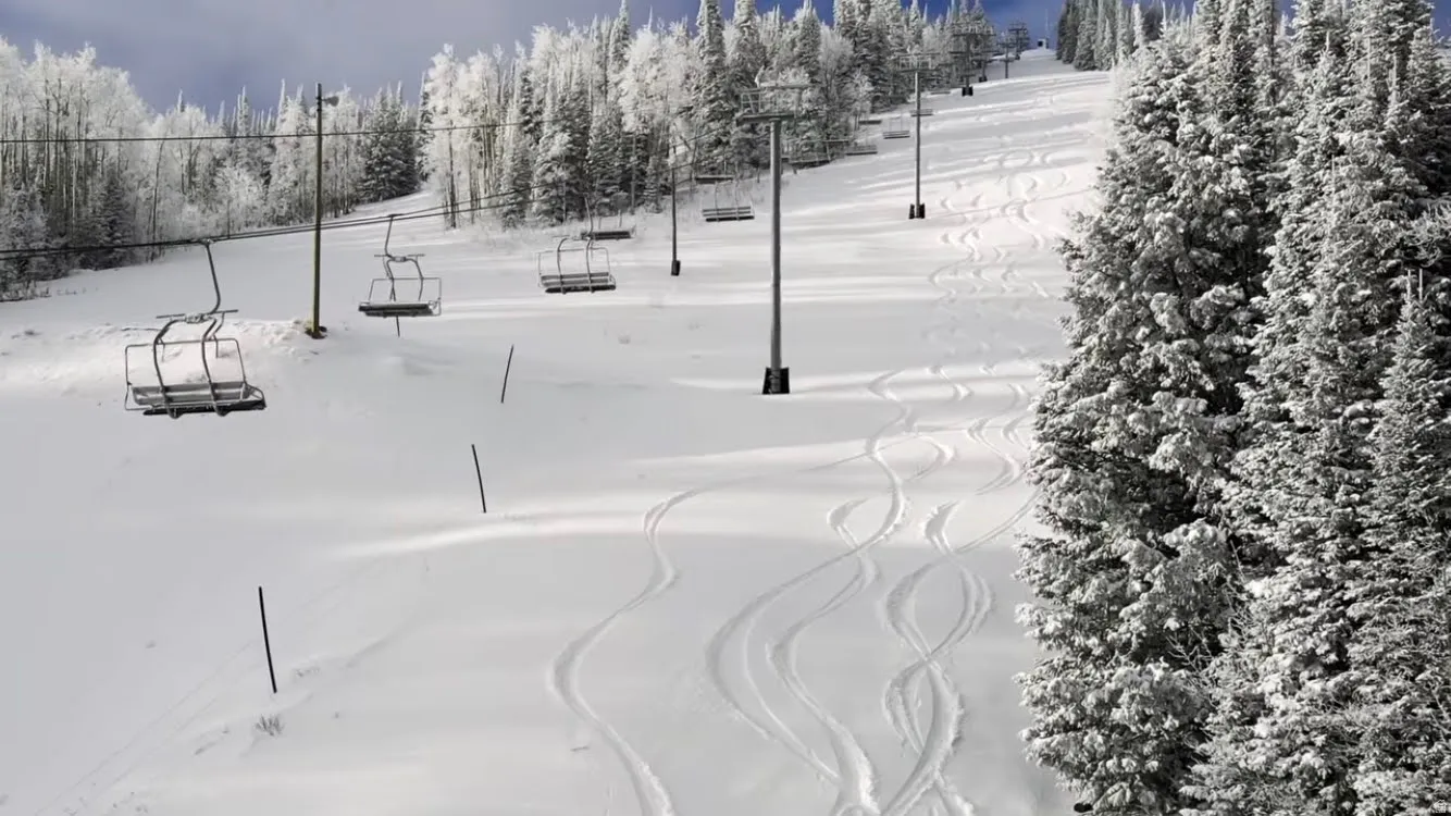 Snow-covered ski slope featuring multiple chairlifts and snow-laden evergreen trees
