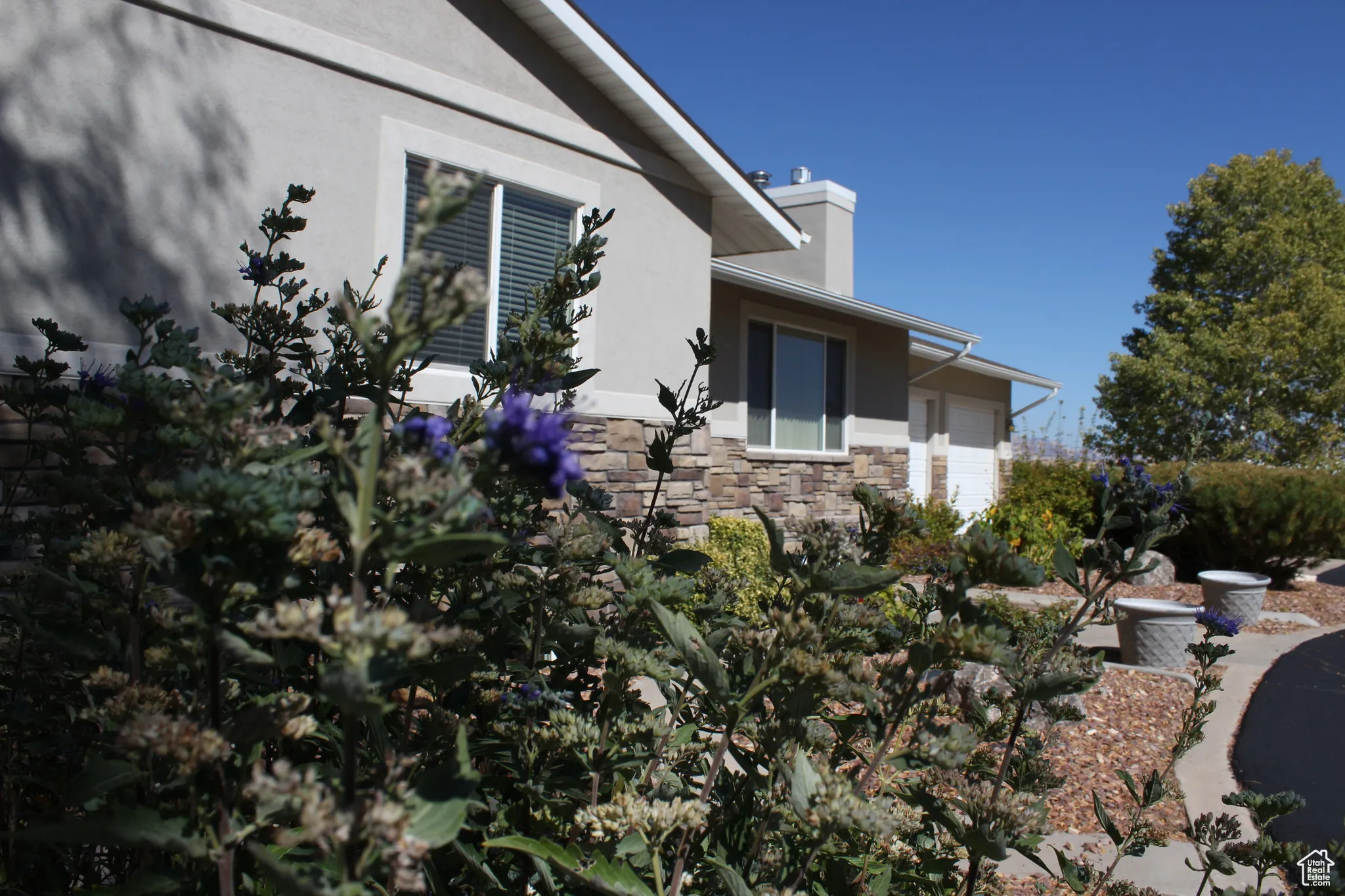 View of side of property with stucco siding, stone siding, and a garage