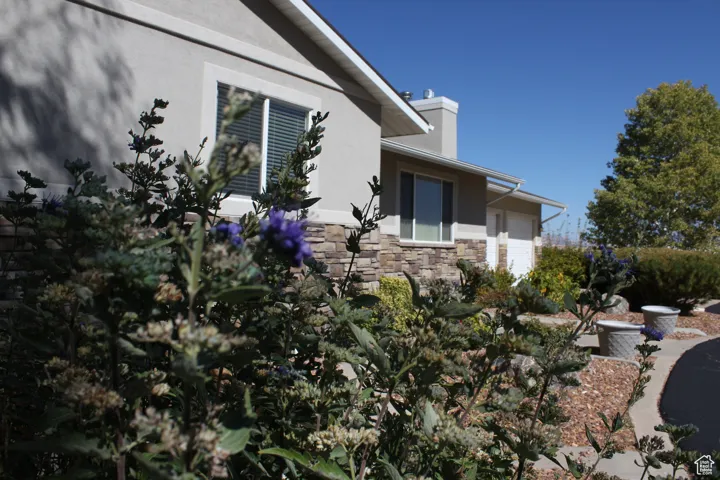 View of side of property with stucco siding, stone siding, and a garage