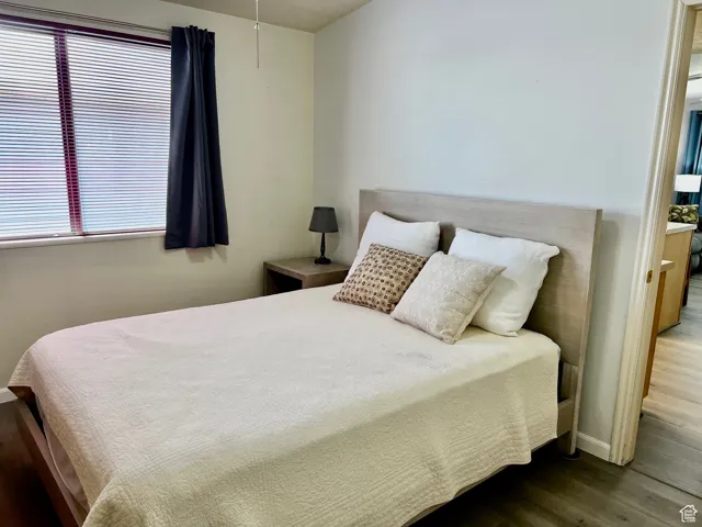 Bedroom with baseboards, multiple windows, ensuite bathroom, and wood finished floors