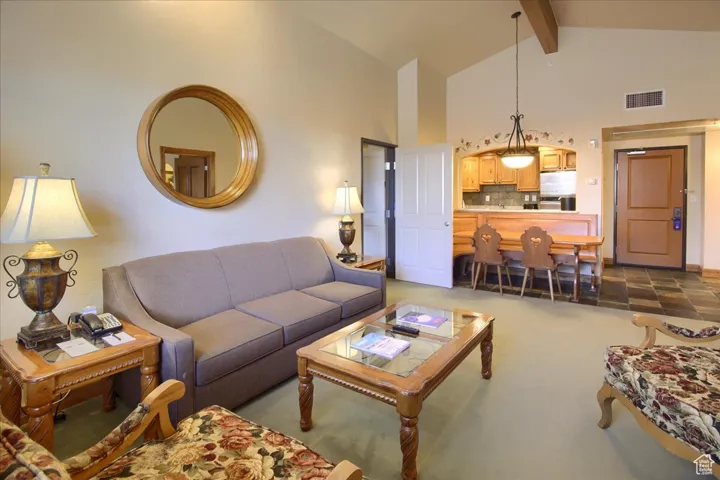 Carpeted living room featuring beamed ceiling and high vaulted ceiling