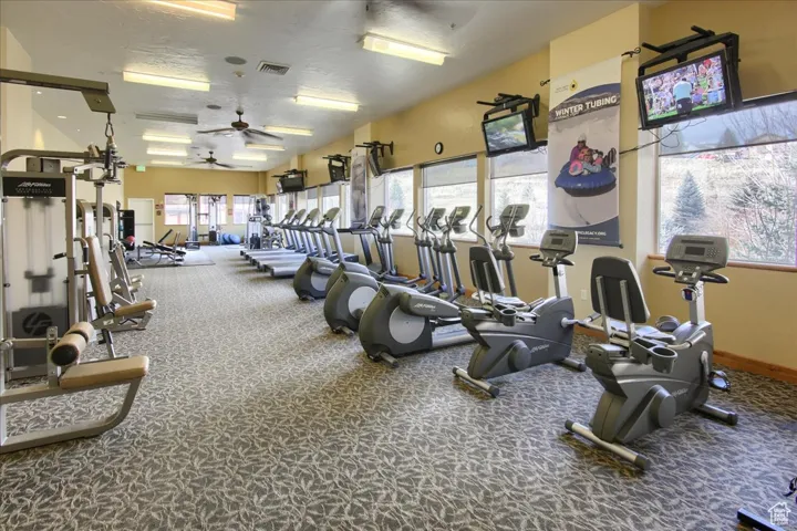 Gym with ceiling fan, a textured ceiling, and carpet