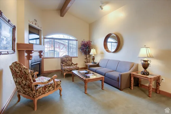 Living room featuring a tile fireplace, carpet, and vaulted ceiling with beams