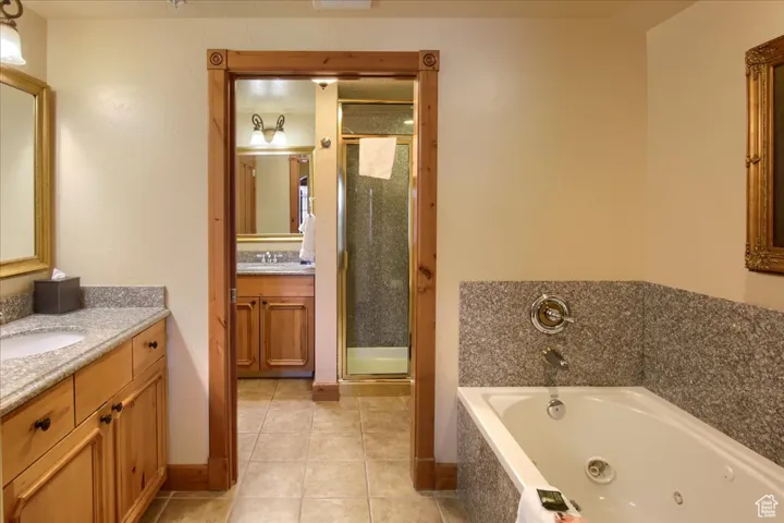 Bathroom with independent shower and bath, vanity, and tile patterned flooring