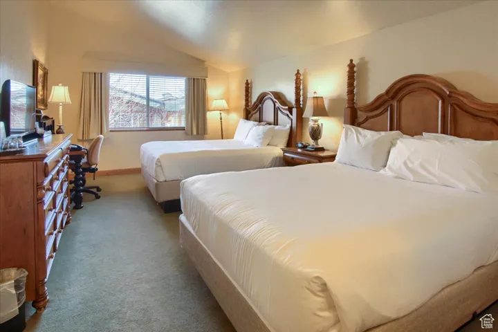 Bedroom with light carpet and vaulted ceiling