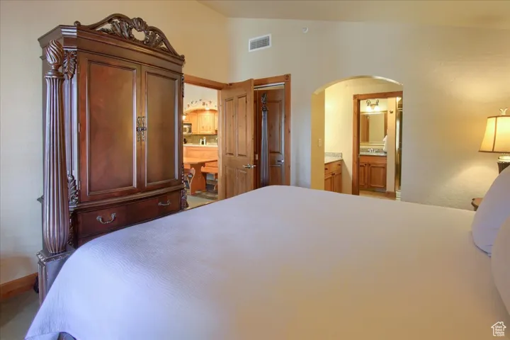 Bedroom featuring lofted ceiling and ensuite bath