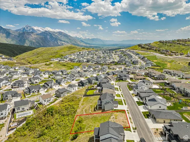 Aerial view of residential area with property boundaries highlighted and a mountainous background