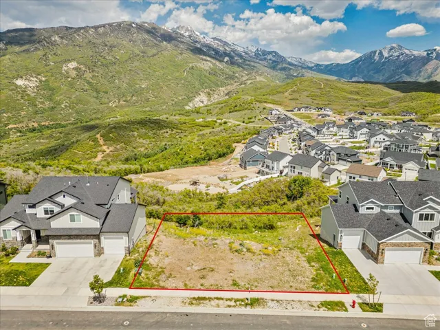 Aerial view of residential area featuring a mountain backdrop and property parcel outlined