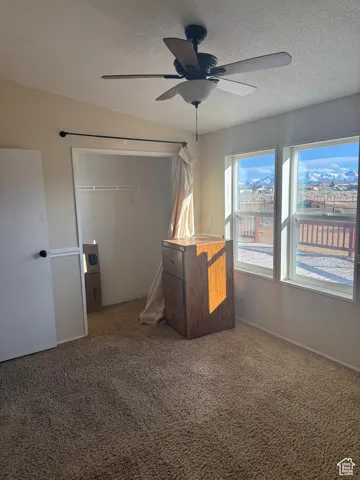Unfurnished bedroom with ceiling fan, carpet floors, a textured ceiling, and a closet