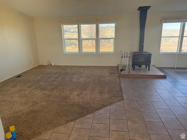 Unfurnished living room with tile patterned flooring and a wood stove