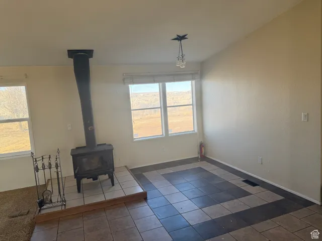 Unfurnished living room with dark tile patterned flooring and a wood stove