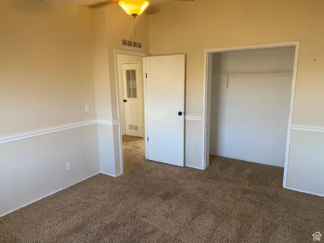Unfurnished bedroom with a closet and dark colored carpet