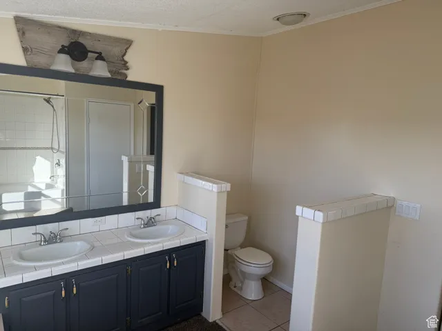 Bathroom with tile patterned flooring, vanity, walk in shower, toilet, and crown molding