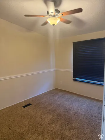Unfurnished room with ceiling fan, a textured ceiling, and carpet flooring