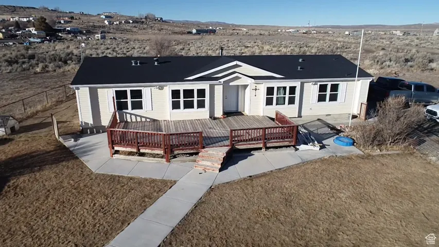 Back of house featuring a deck with mountain view and a lawn