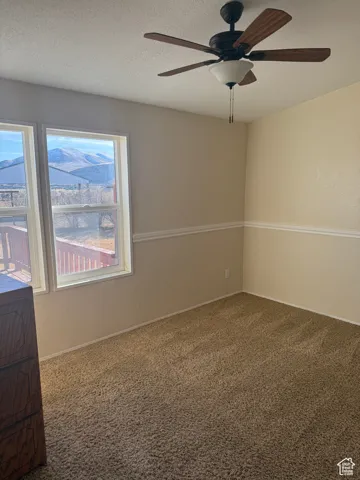 Carpeted spare room featuring ceiling fan and a textured ceiling