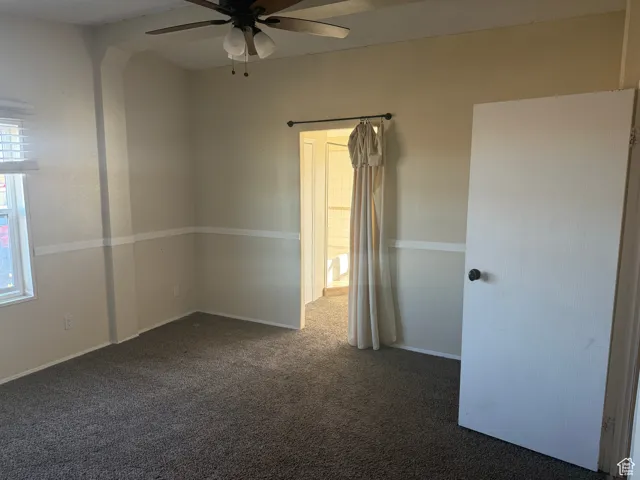 Spare room featuring dark carpet and ceiling fan