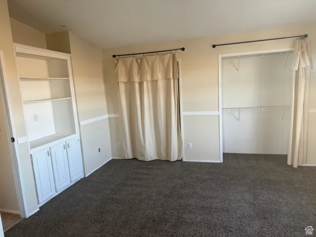 Unfurnished bedroom featuring dark carpet