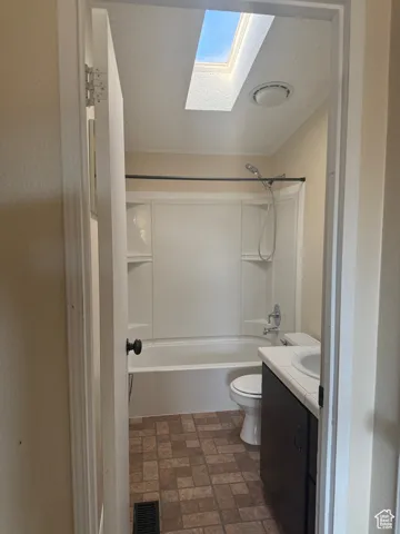 Full bathroom featuring a skylight, vanity, shower / bathing tub combination, a textured ceiling, and toilet