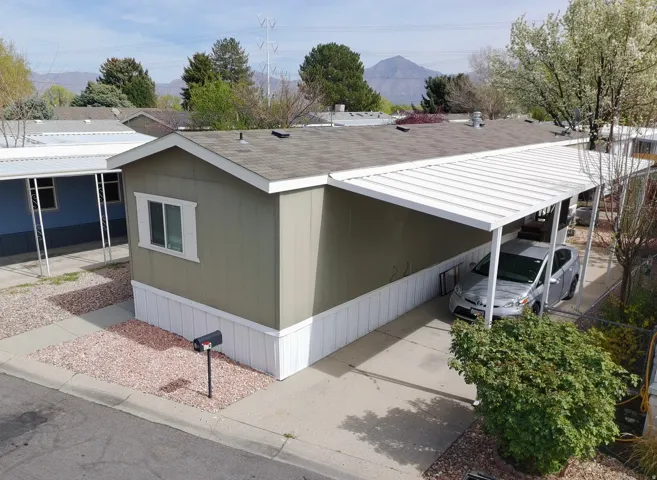 View of home's exterior featuring an attached carport, a mountain view, and roof with shingles