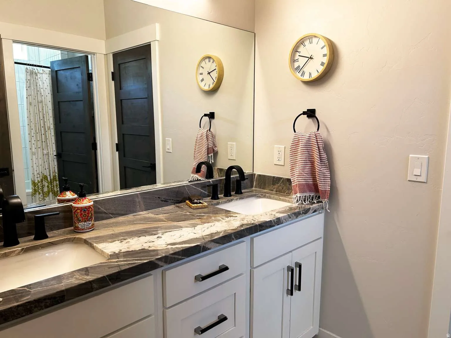 Dual vanity featuring a stone-look countertop, white cabinetry with dark hardware, and integrated sinks