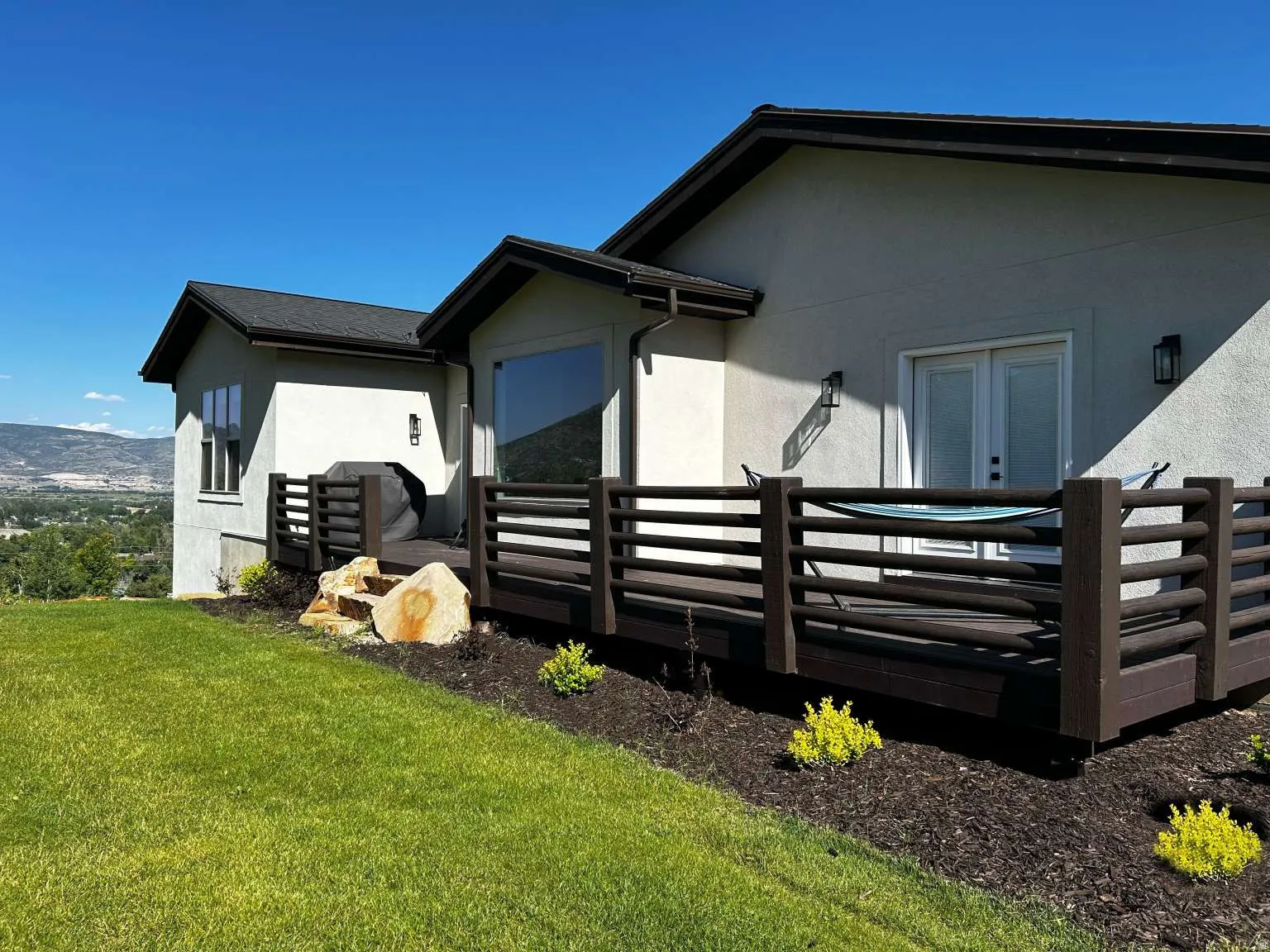 Exterior stucco finish with dark trim, featuring a spacious outdoor deck with dark railings