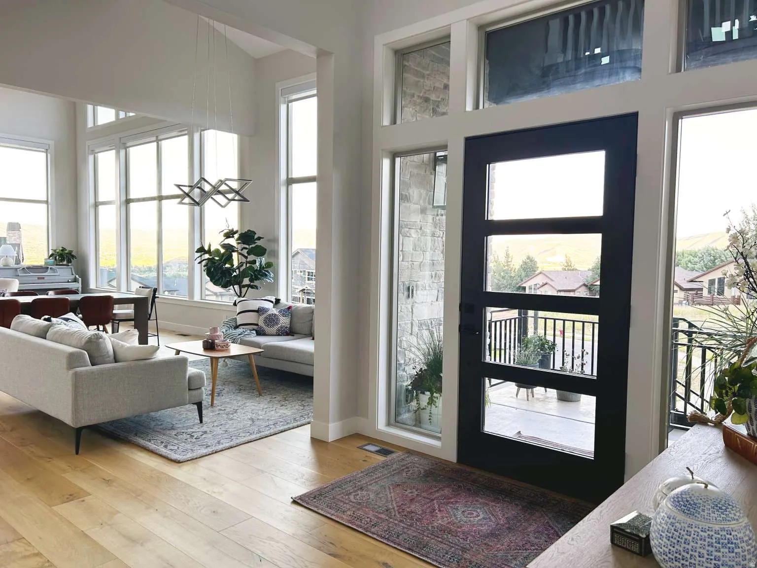 Modern entry door with multiple glass lites and sidelights, complemented by light wood-finish flooring