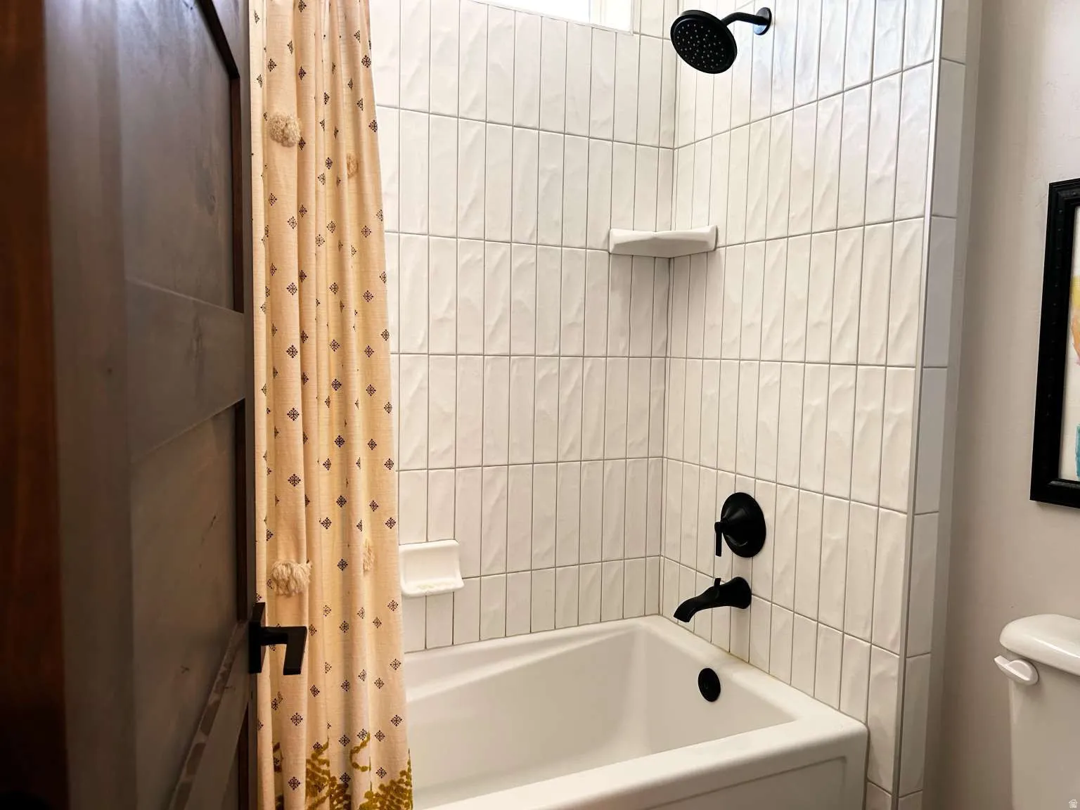 Bathtub and shower combination featuring vertical white tile surround